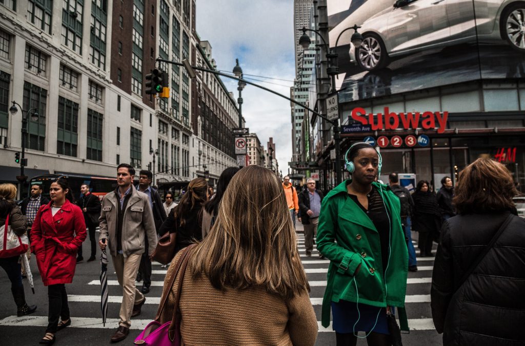 A bustling city street with diverse individuals navigating their day, capturing the dynamic experience of moving abroad and fitting in. Featured on Raided by Tintin.