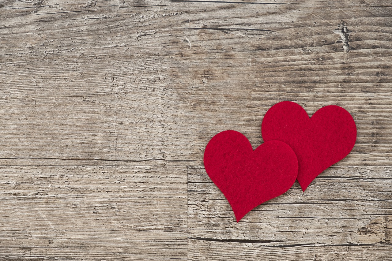 Two red felt hearts on a rustic wooden background, symbolizing love and connection, perfect for Raided by Tintin's article on Valentine’s Day gifts