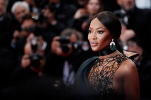 Naomi Campbell gracing the red carpet in an elegant black gown, epitomizing her status as a global fashion icon and inspiration, featured on Raided by Tintin.