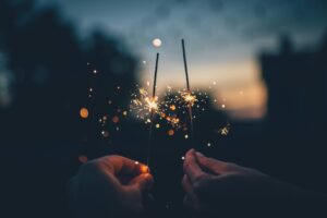 Two hands holding sparklers against a twilight background, symbolizing fresh beginnings and inspiration for New Year’s resolutions. Featured on Raided by Tintin