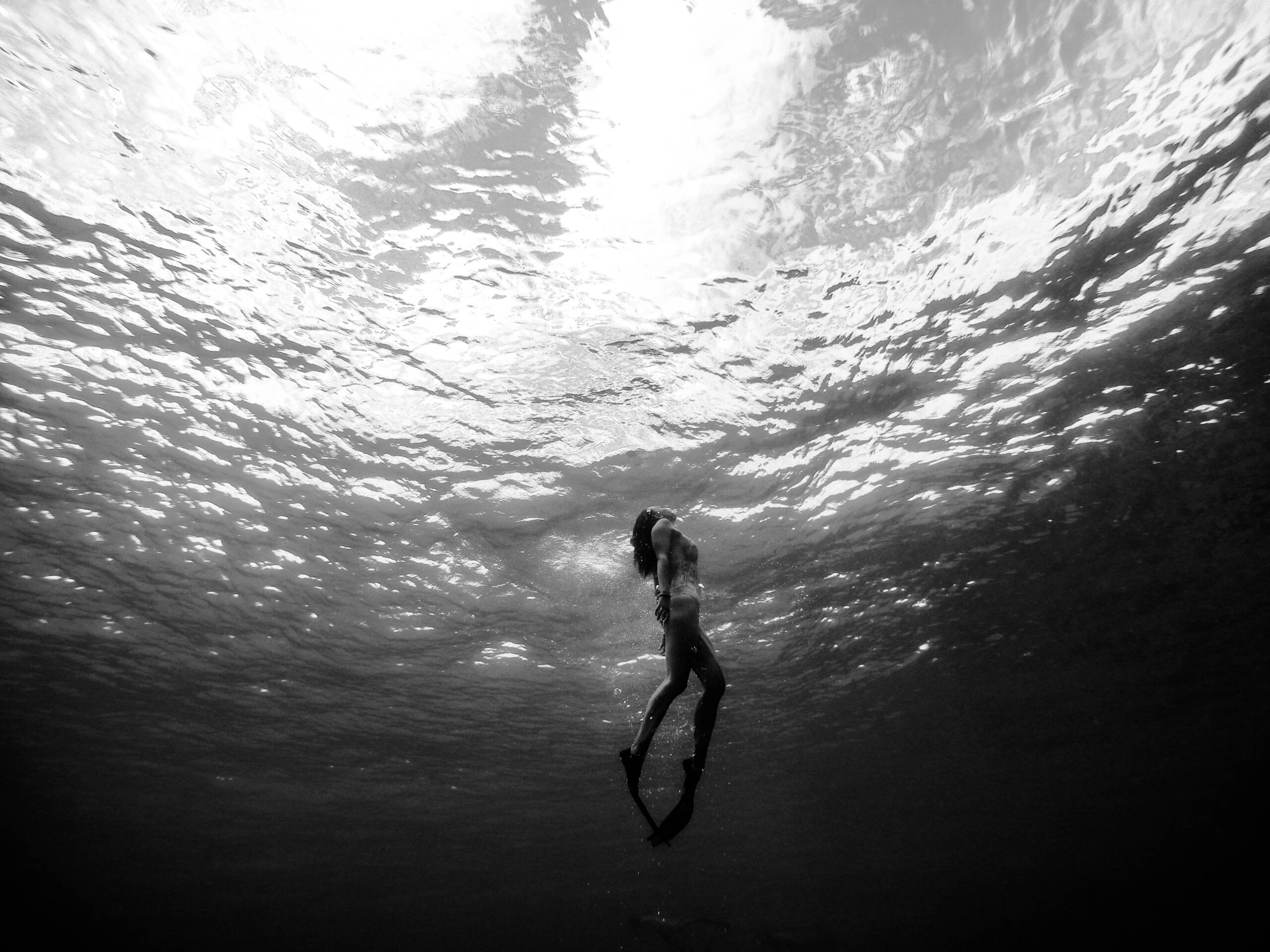 Black and white image of a diver gracefully floating underwater, symbolizing the calm and focus needed for self-control. Featured in the article 'Mastering Self-Control: How to Stay Strong When Temptation Strikes' on Raided by Tintin.