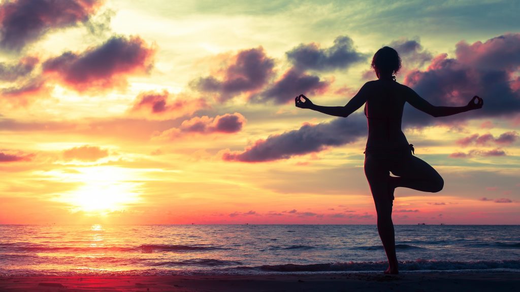 A silhouette of a person practicing yoga on the beach at sunset, symbolizing balance and self-control, featured in the article 'Mastering Self-Control: Staying Strong Against Temptation' on Raided by Tintin.